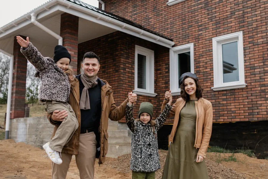 Familie mit zwei Kindern freut sich vor ihrem neuen Haus